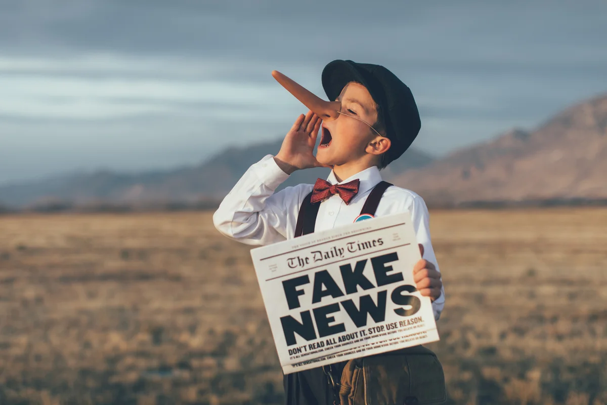 Young boy dressed as Pinocchio holding a newspaper with a "Fake News" headline, illustrating the misinformation generated by hallucinations